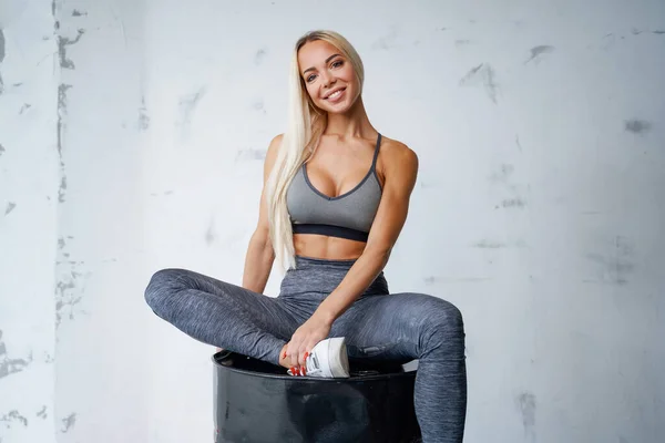 Blond in grauer Sportbekleidung posiert auf schwarzem Lauf im Studio — Stockfoto