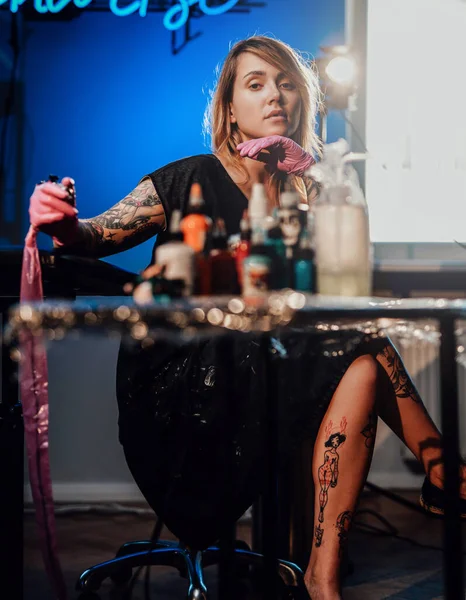 Tattoo master seduta sulla sedia e in posa nel suo piccolo salone — Foto Stock