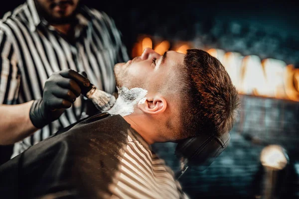 Barber appliquant du savon sur son client dans son salon — Photo