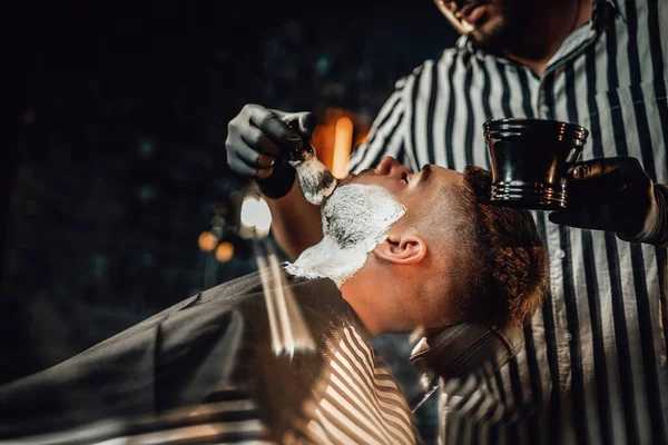 Peluquero aplica jabón a su cliente en su salón —  Fotos de Stock