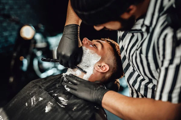 Peluquero caucásico afeitando a un cliente en elegante salón —  Fotos de Stock