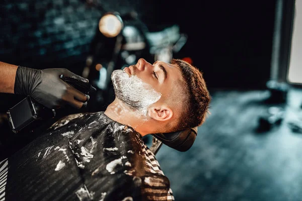 Un peluquero que usa un pulverizador para limpiar a su cliente de jabón —  Fotos de Stock