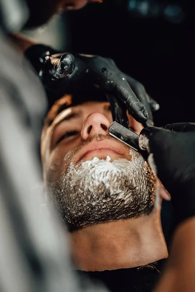 Brutal cara está barbeando por cabeleireiro profissional — Fotografia de Stock