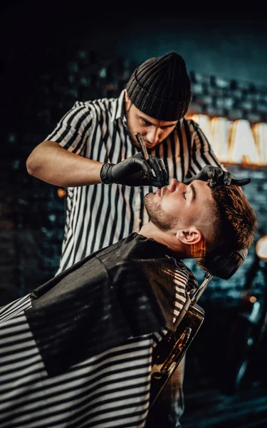 Peluquero profesional cortando barba de su cliente en salón —  Fotos de Stock