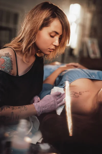 纹身大师与她的客户在闪亮明亮的工作室 — 图库照片
