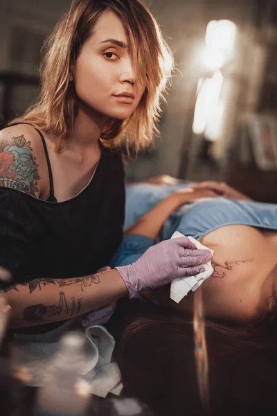 Maestro del tatuaje con su cliente en un estudio brillante e iluminado —  Fotos de Stock