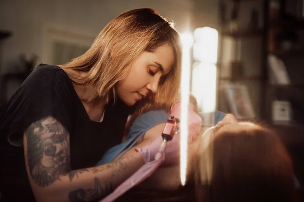 Professional tattoo master painting his client in shiny room — Stock Photo, Image