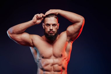 Sakallı ve bıyıklı bir sporcu saçlarını tarıyor.