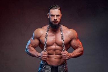 Sakallı, çelik zincirli ve poz veren vücut geliştirici.