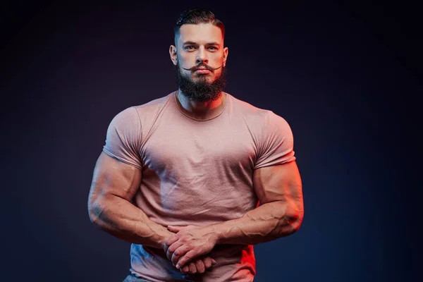Schöner Bodybuilder mit Bart posiert vor dunklem Hintergrund — Stockfoto