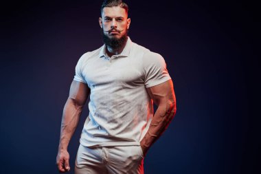 Beyaz gömlekle poz veren kaslı vücutlu güçlü adam.