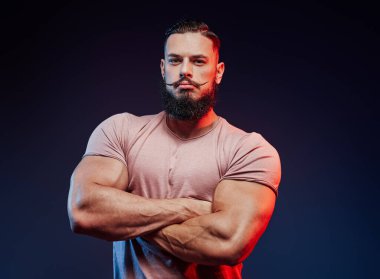 Havalı saç stili ve sakallı sporcu koyu arka planda kalıyor.