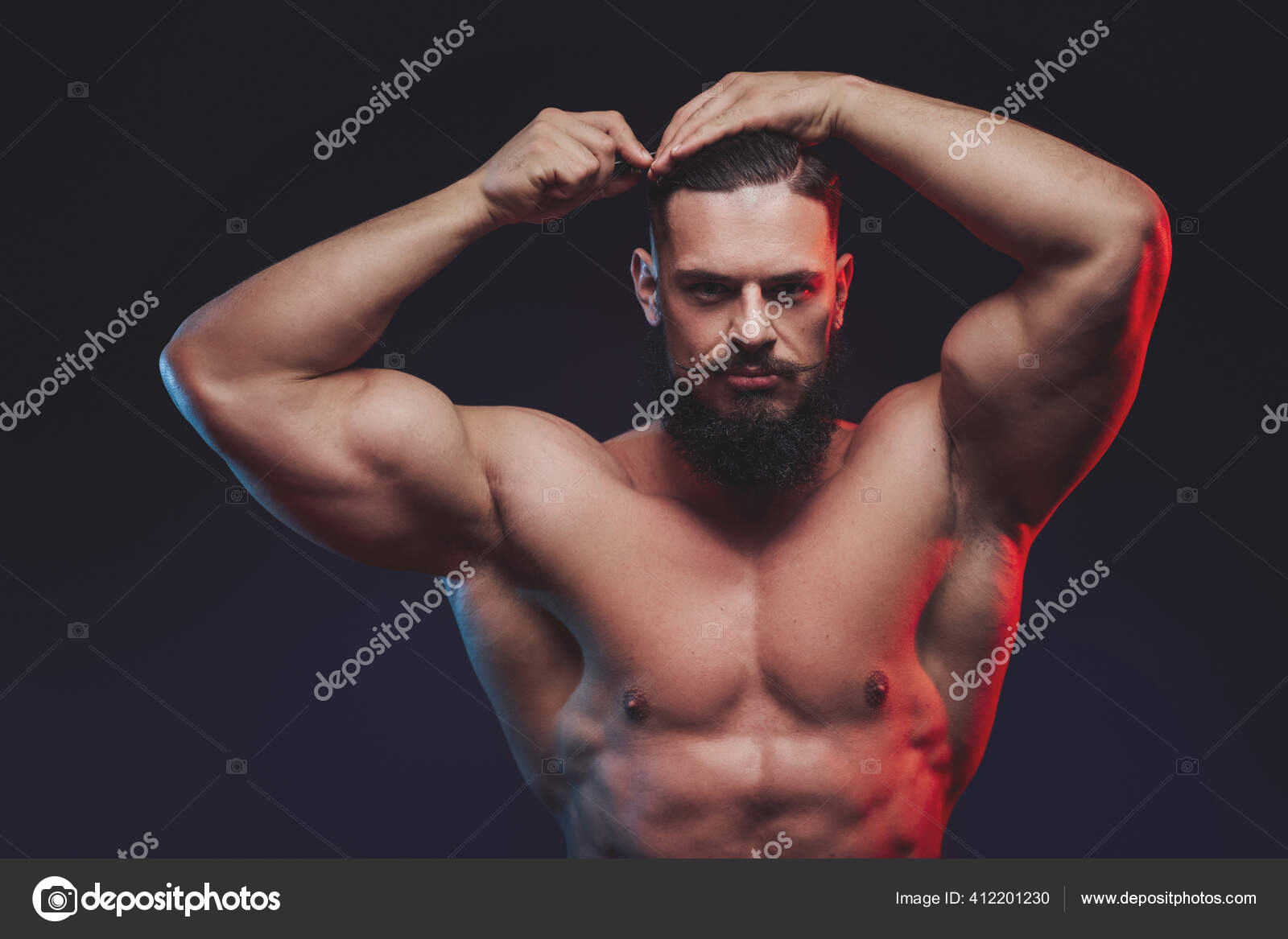 Brutal bodybuilder with beard posing with hairbrush in studio Stock