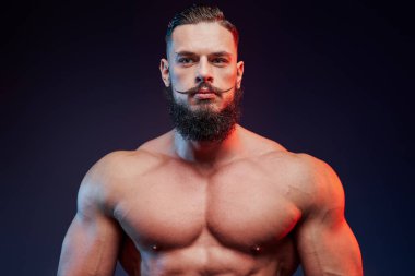 Karanlık arka planda çıplak vücut pozu veren güçlü bir adam.