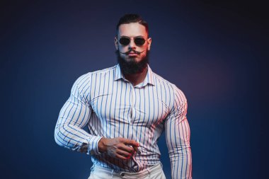 Elinde puroyla poz veren zarif vücutgeliştirici.