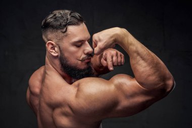 Gri arka planda poz veren kaslı adam.