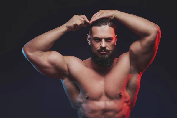 Brutal bodybuilder with beard posing with hairbrush in studio — Stock Photo, Image