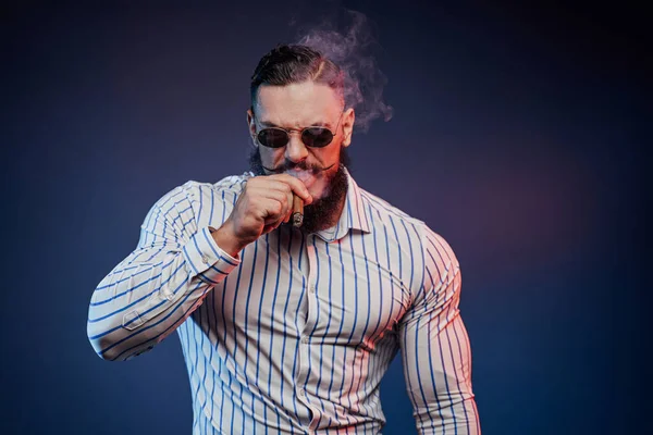 Bärtiger muskulöser Kerl in gläserner Zigarre und posiert — Stockfoto