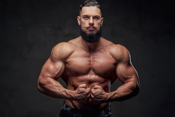 Bodybuilder confiance en soi posant en arrière-plan sombre — Photo