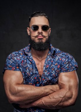Çapraz elle poz veren büyük pazılı moda vücut geliştirici.