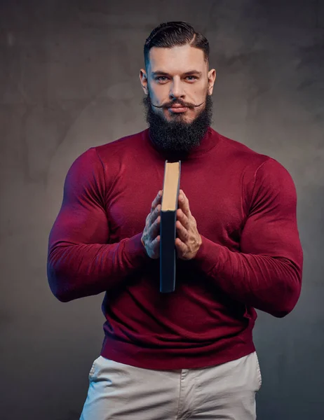 Slimme bodybuilder in trui poseren holding book — Stockfoto