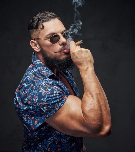 Bodybuilder smoking cigar with sunglasses in gray background — Stock Photo, Image