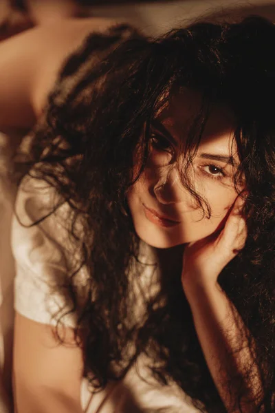 Красива жінка з чорними хвилястими волоссям лежить на ліжку — стокове фото