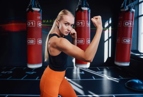 Pozytywna kobieta pozująca z workami bokserskimi w tle — Zdjęcie stockowe