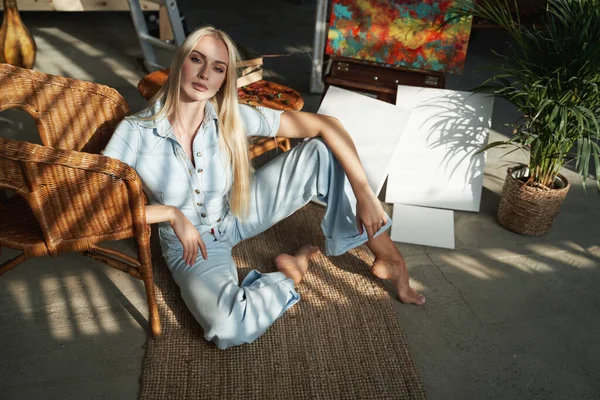 Vrouwelijke kunstenaar met blond haar poseren op tapijt thuis — Stockfoto
