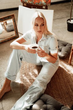 Kadın sanatçı yastıkların etrafında dinleniyor.