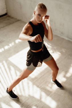 Sarışın sporcu, beyaz stüdyo odasında dövüşüyor.