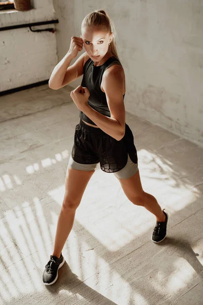 Rubia deportiva permaneciendo en pose de lucha en la habitación del estudio blanco — Foto de Stock