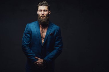Serious bearded guy posing in suite in dark background clipart