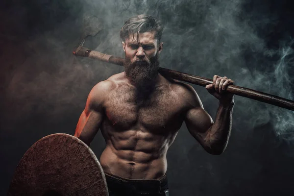 Frenzied viking in dark background with axe and shield — Stock Photo, Image