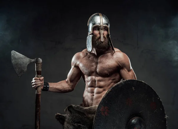 スポットライト付きスタジオで斧と盾を持つ北欧の戦士 — ストック写真