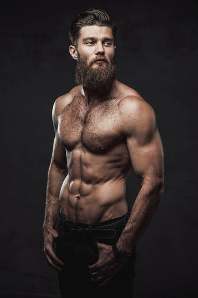 Naked and muscular guy posing in dark background