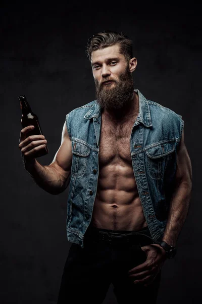 Moderně oblečený pohledný chlap s lahví v tmavém pozadí — Stock fotografie