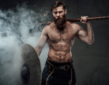 Siyah duman arka planında balta ve kalkan ile kaslı viking