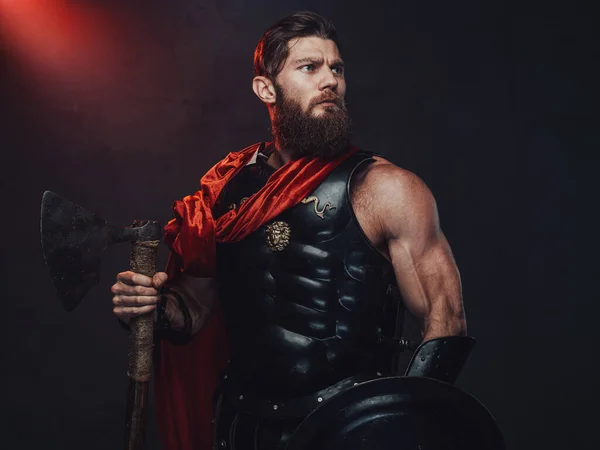 Romain guerrier blindé avec cape et hache dans une pièce sombre — Photo