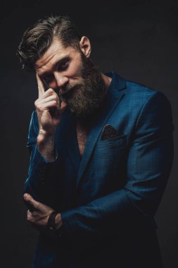 Karanlık arka planda poz veren süit sakallı adam.