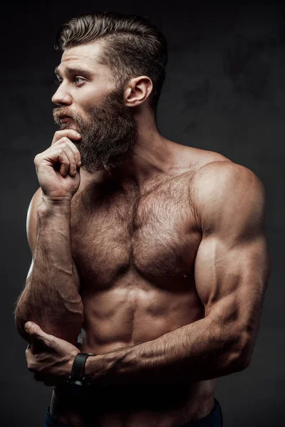 Muskulös skäggig kille poserar tittar bort i studio — Stockfoto
