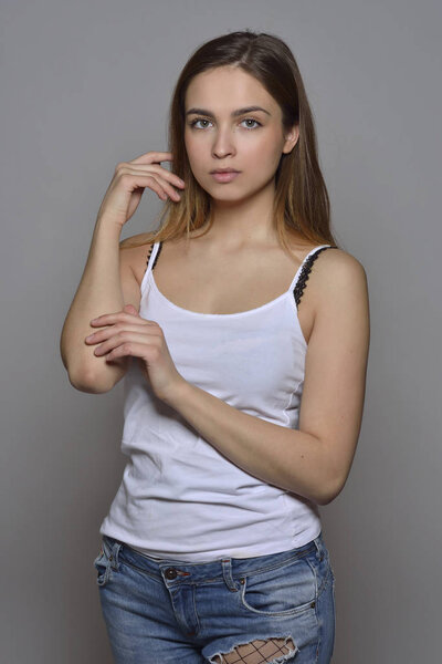 Эмоциональный портрет красивой женщины в верхней части и джинсах. Студийные съемки на сером фоне
.