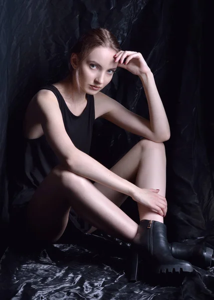 黒の上で美しい女性 靴の背景が暗いスタジオで座っています — ストック写真