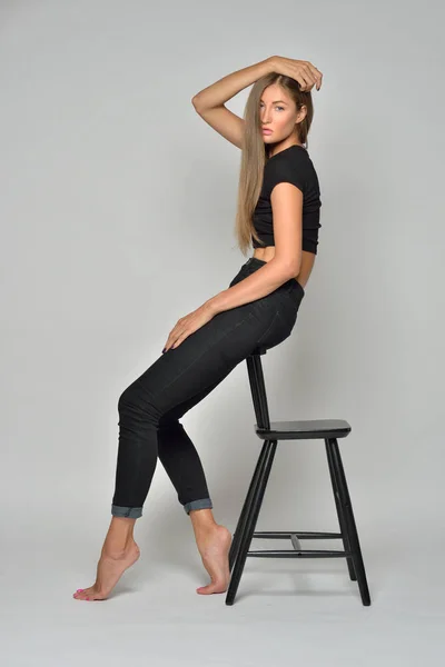 Sexy belle femme en noir assis sur chaise haute . — Photo