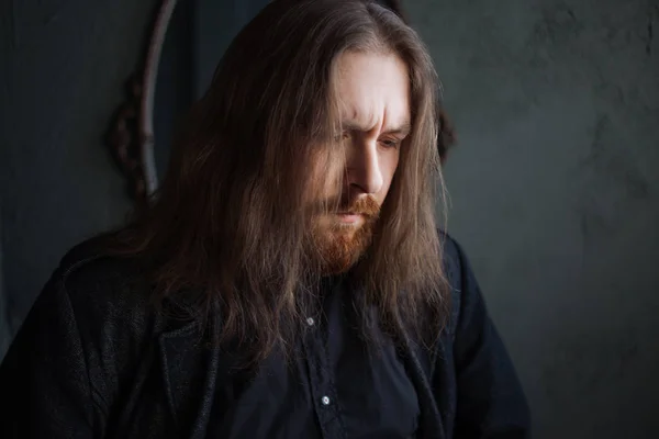 Portrait d'homme aux cheveux longs et à la barbe en vêtements noirs sur fond sombre — Photo