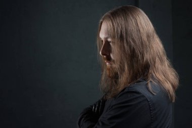 Uzun saç ve sakal koyu arka plan üzerinde siyah giysili adam portresi