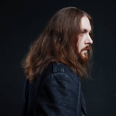 Uzun saç ve sakal koyu arka plan üzerinde siyah giysili adam portresi