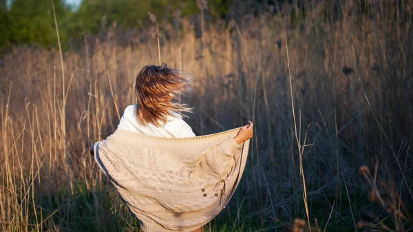 Милая очаровательная девушка летом в поле. Молодая женщина счастлива и чувствует себя свободно на открытом воздухе. Вид сзади — стоковое фото