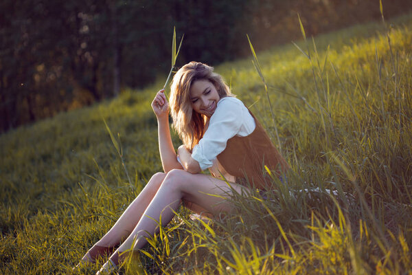 Beautiful young woman enjoying a picnic in nature. Girl sitting on the grass, rest, relaxation