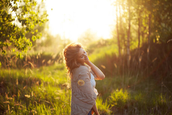 Cute charming girl in summer in the field. Young woman is happy and feels free, outdoors
